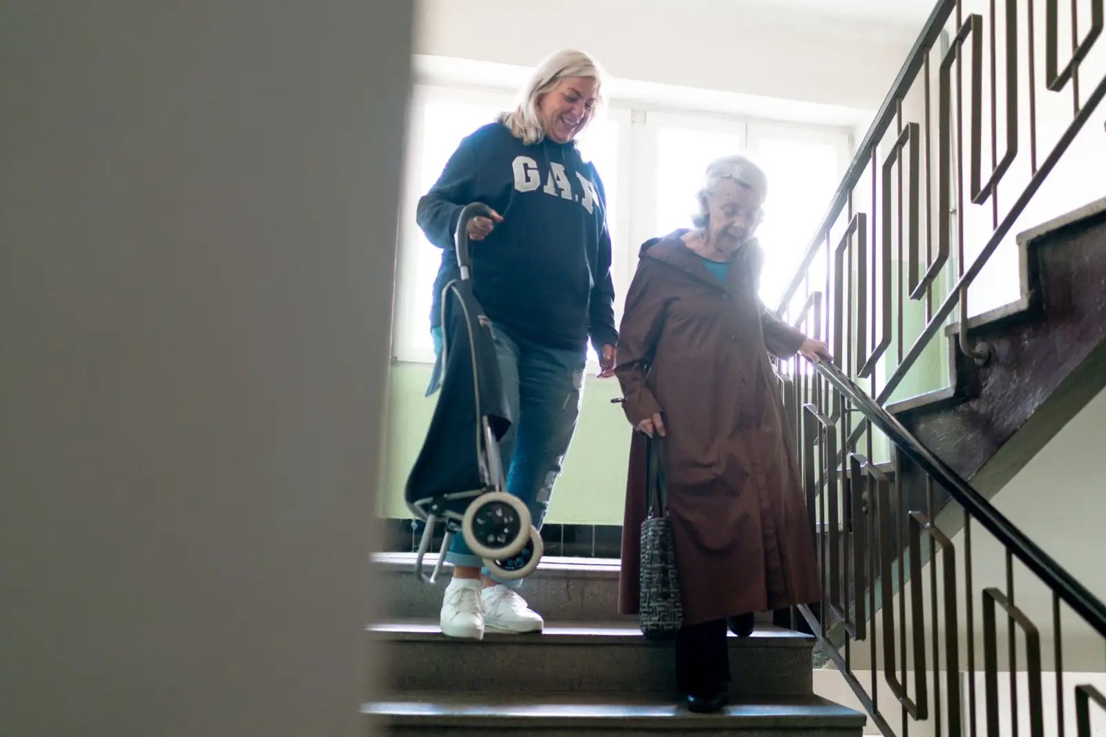 Monte-escalier dans le Maine-et-Loire : aide à domicile accompagnant une dame âgée dans l'escalier